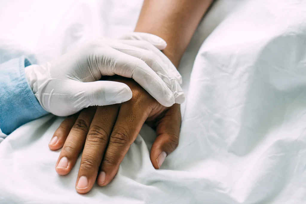 A nurse hand holding a patient who just went through spine surgery.