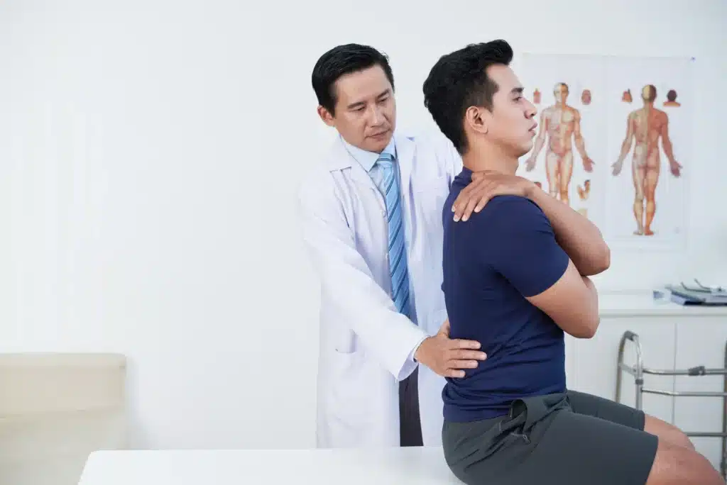 Doctor performing a spine exam on a male patient