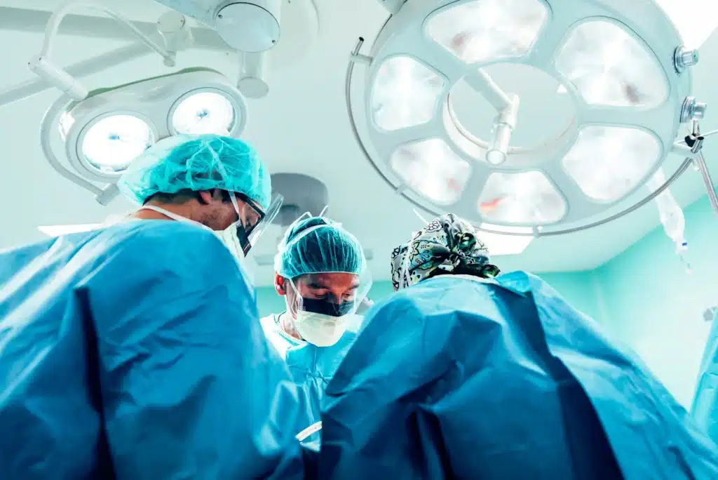 Doctors in blue surgery gear operating in a surgery room