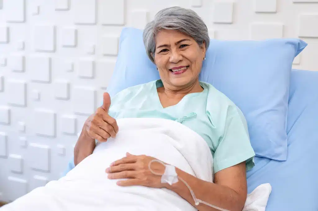 Woman laying on hospital bed happy with a thumbs up