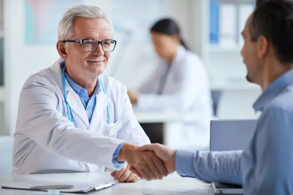 male doctor smiling and shaking hands with a patient