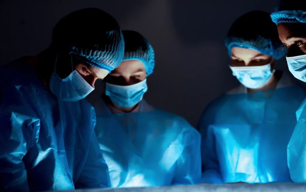 four surgeons in a dark surgery room