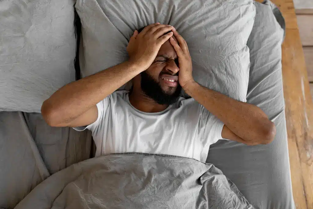 Man in bed suffering a headache or migraine