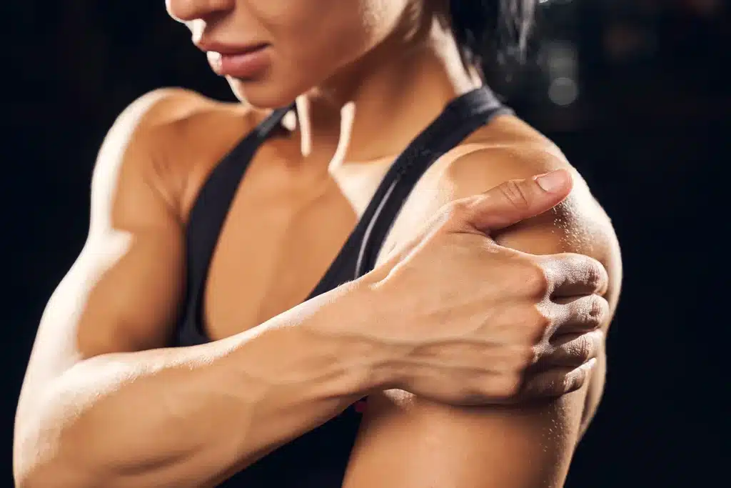 Athletic woman holding her shoulder in pain