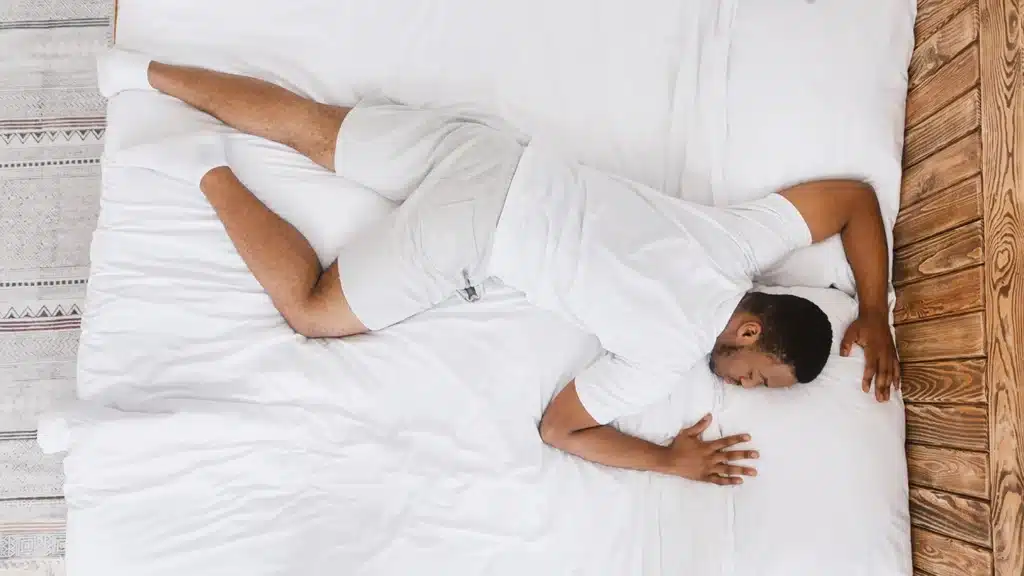 Man lying in bed in stomach sleeping position