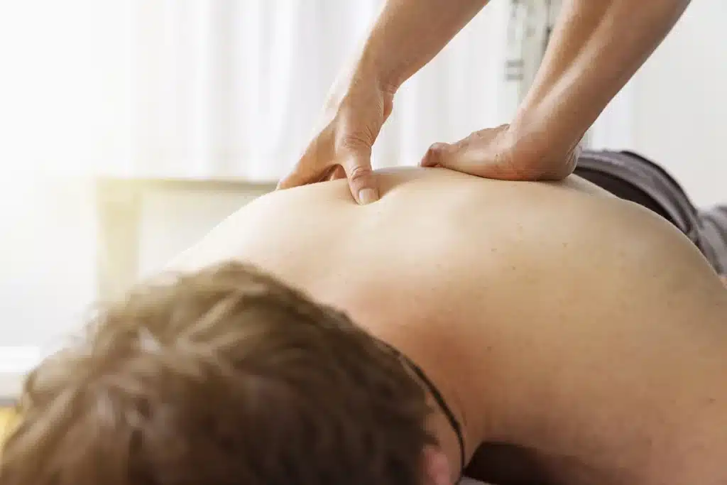 Man lying down and being treated by a massage therapist
