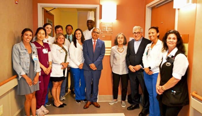 Dr. Saathi (center) was honored with a plaque outside an isolation room dedicated in his honor by Stanley and Dr. Marion Bergman (3rd and 4th from right). They posed with members of their caregiver team, including nurses and a member of the Food & Dining Services staff. Photo courtesy of Mather Hospital