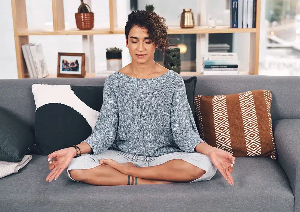 A woman meditating on her couch