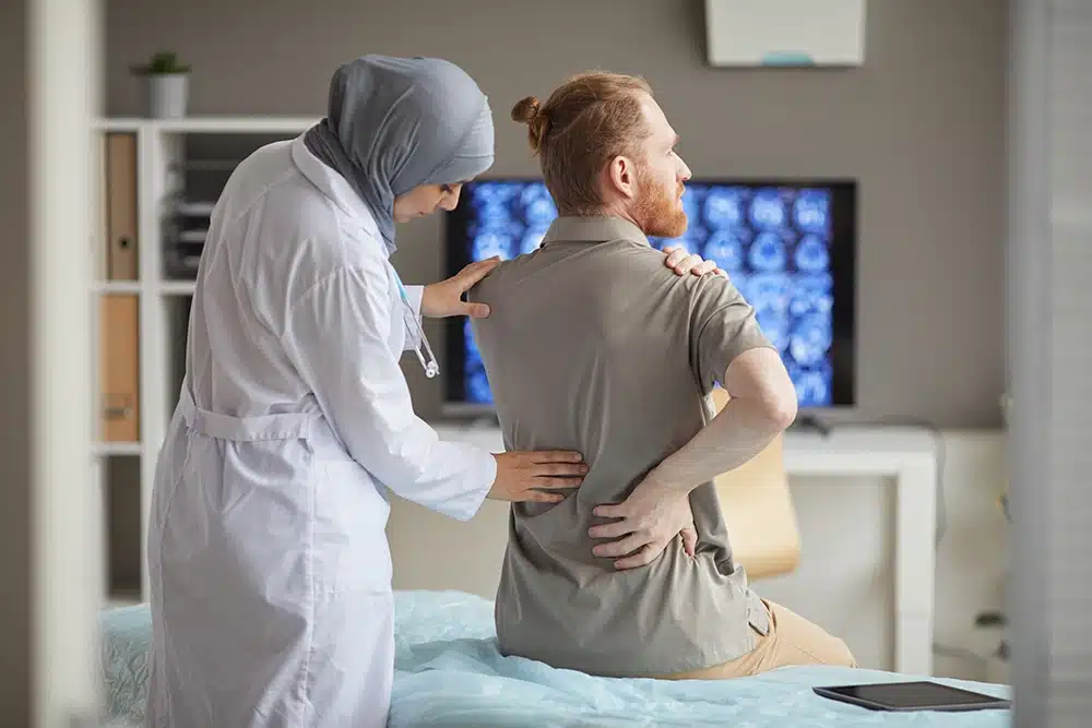 A doctor helping a patient with his back pain