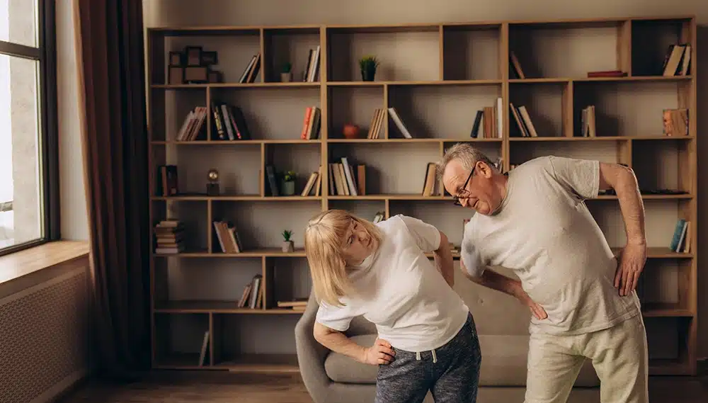 two adults stretching their back to manage pain