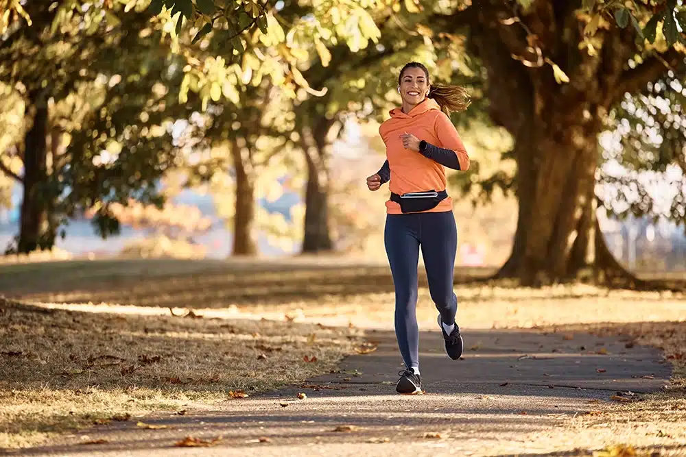 Woman exercising, running through a park