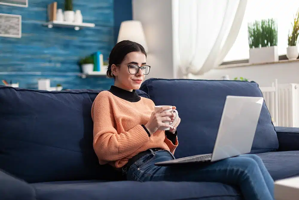 woman sitting on the couch reading an online article