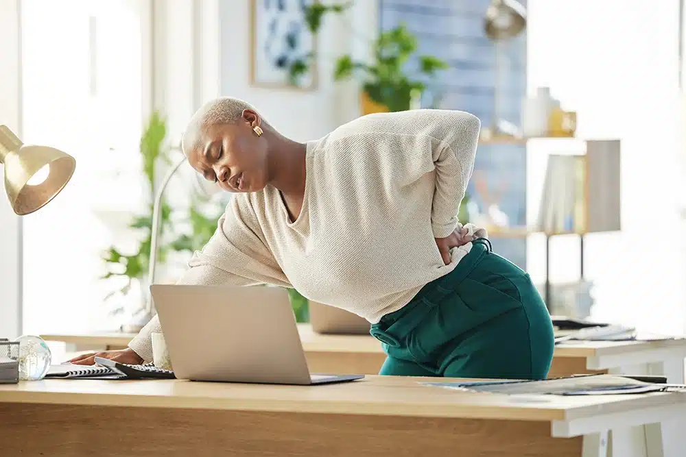 Woman holding her back in pain at her office