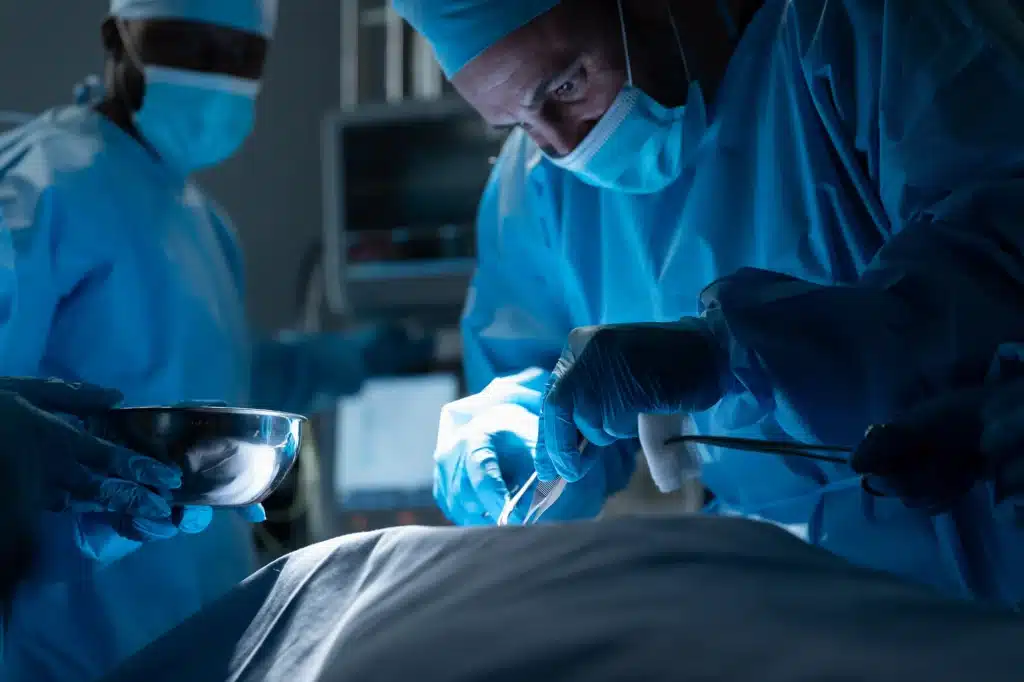 Focused surgeon performing minimally invasive surgery with advanced medical equipment in a dimly lit operating room.