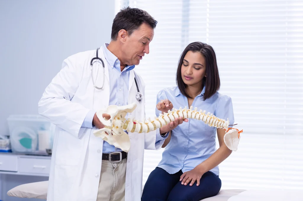 Spine specialist educating patient about thoracic spinal health using a model.
