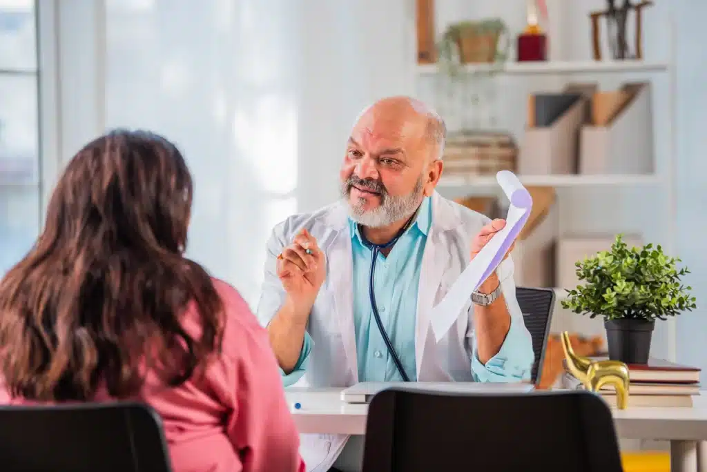 Elderly Doctor Consulting with Young Female Patient in Clinic