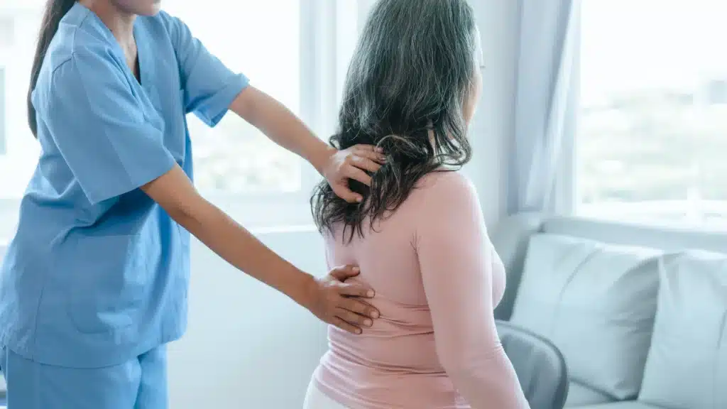 Physiotherapist assisting a patient recovering from minimally invasive spinal fusion surgery.