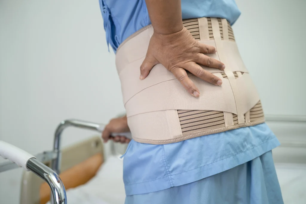 Post-surgery patient wearing a back support belt after spinal fusion surgery.