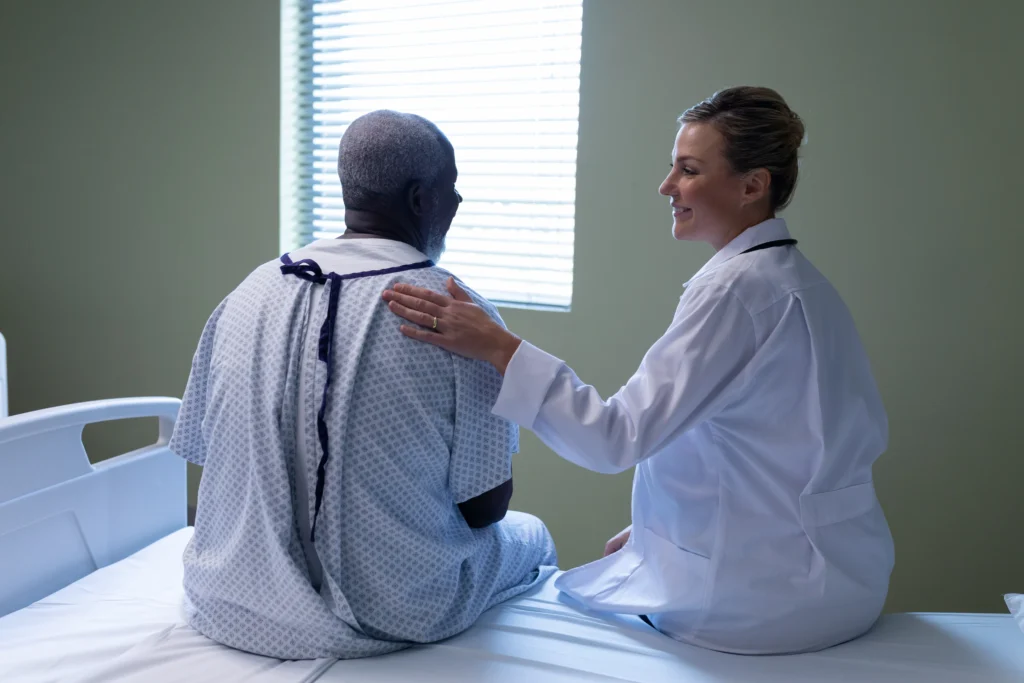 Doctor comforting an older male patient, discussing recovery after spinal fusion surgery and disability benefits.