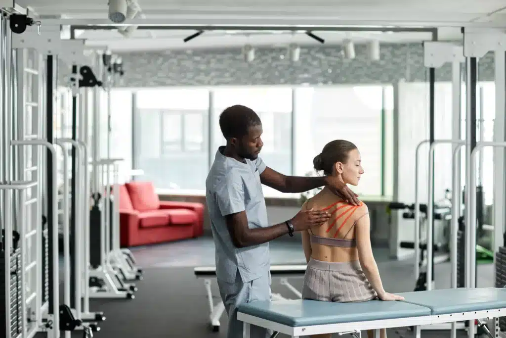 Doctor applying therapeutic tape on patient’s back to aid recovery after spinal fusion surgery.