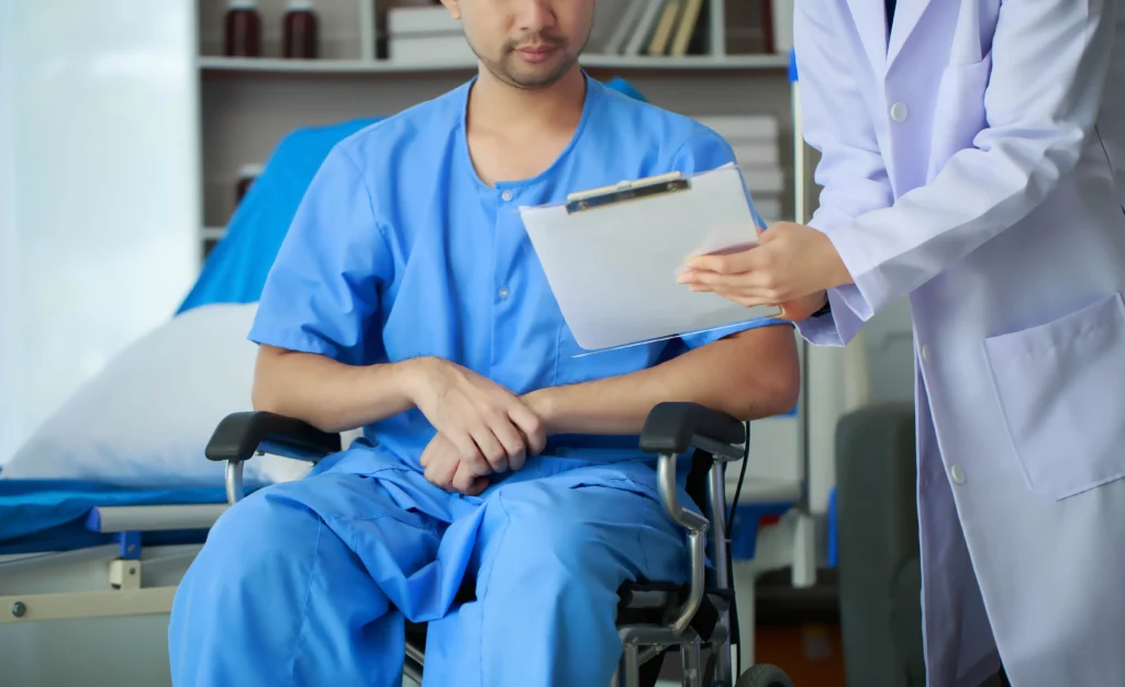 Medical professional consulting with a patient in a wheelchair about spinal fusion and possible long-term disability benefits.