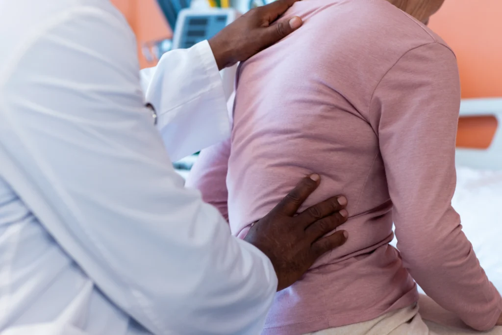 Doctor examining a patient's back as part of a spinal fusion surgery evaluation, highlighting the importance of pre-operative consultation for spinal fusion success rate.