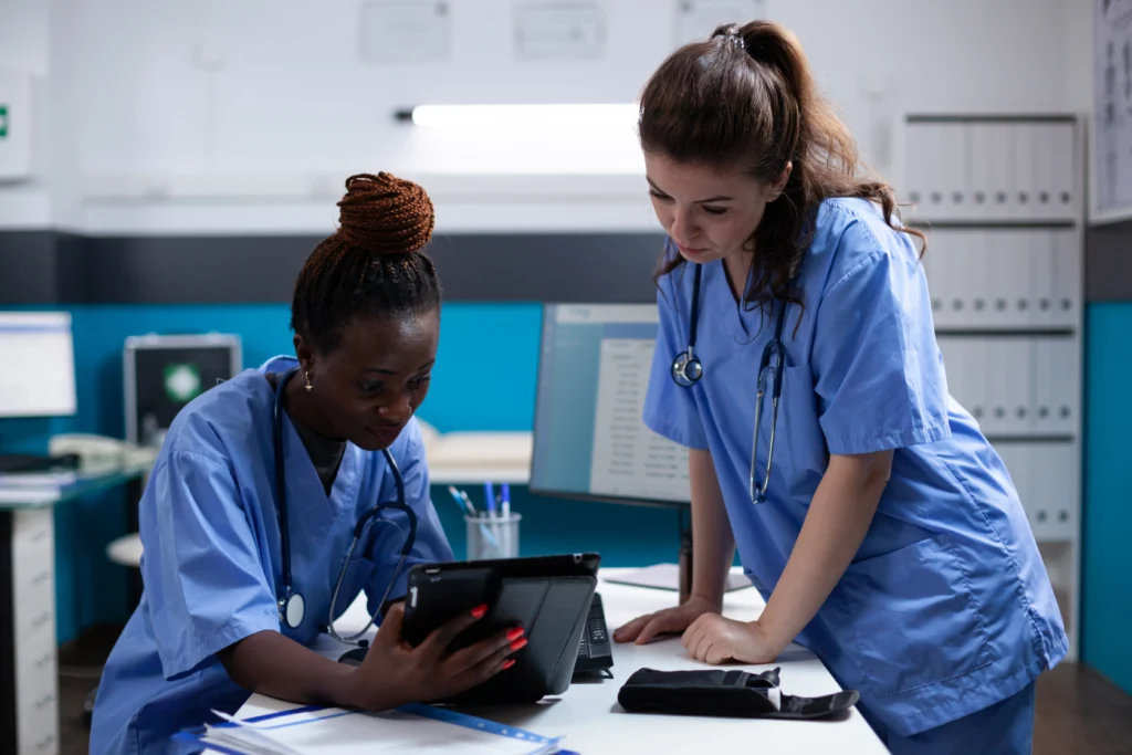 Nurses reviewing spinal fusion patient records on tablet