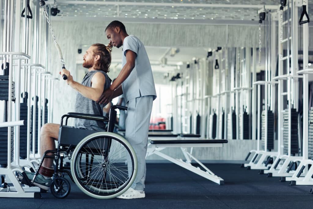 Patient in a wheelchair performing back strengthening exercises in the gym after spinal fusion surgery.