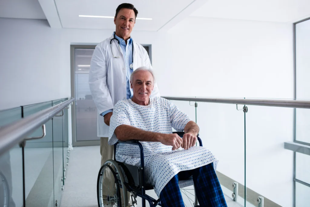 Doctor smiling with senior male patient in a wheelchair after spinal fusion surgery, discussing disability benefits.