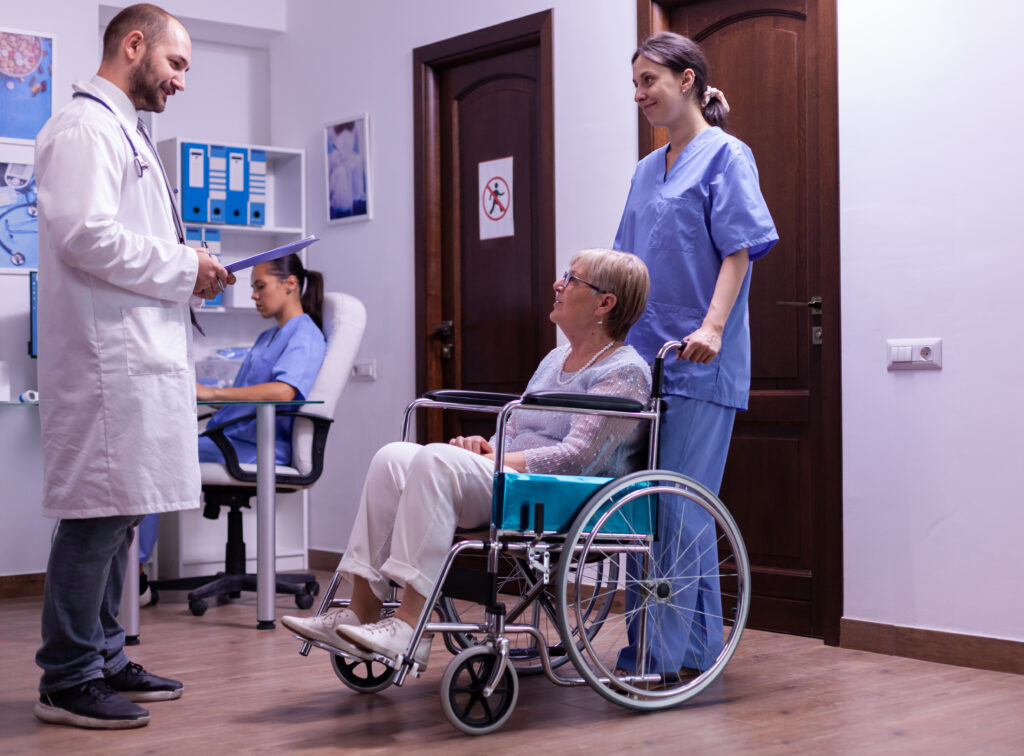 Specialist discussing recovery options with an elderly patient in a wheelchair after spinal fusion surgery.