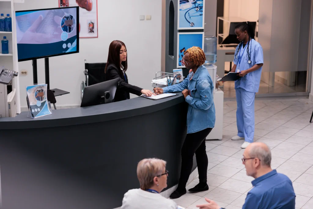 Patient filling out registration form at a healthcare clinic reception, discussing artificial disc replacement surgery costs.