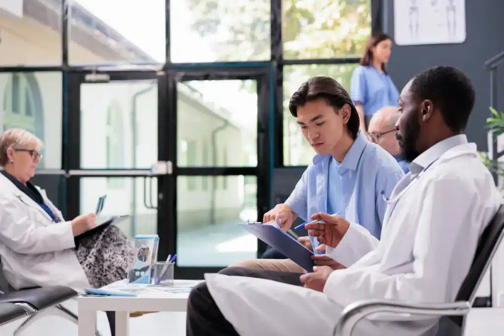 A doctor consulting a patient about spine surgery insurance options in Long Island. The patient reviews documents while discussing treatment coverage.