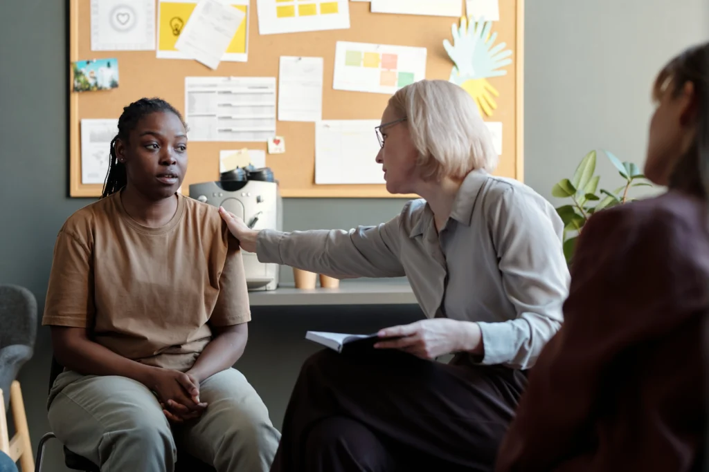 A therapist providing emotional support to a young woman during a counseling session, illustrating therapeutic counseling for pain management.