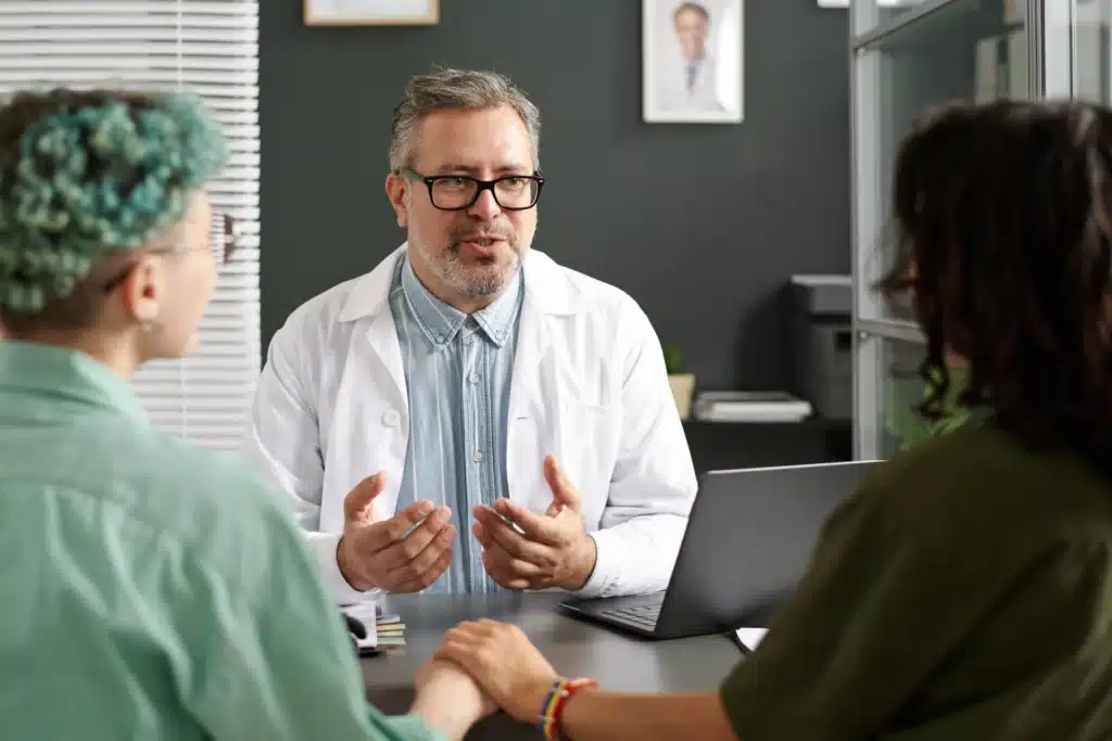 Pain management specialist on Long Island consulting with a couple in a medical office.