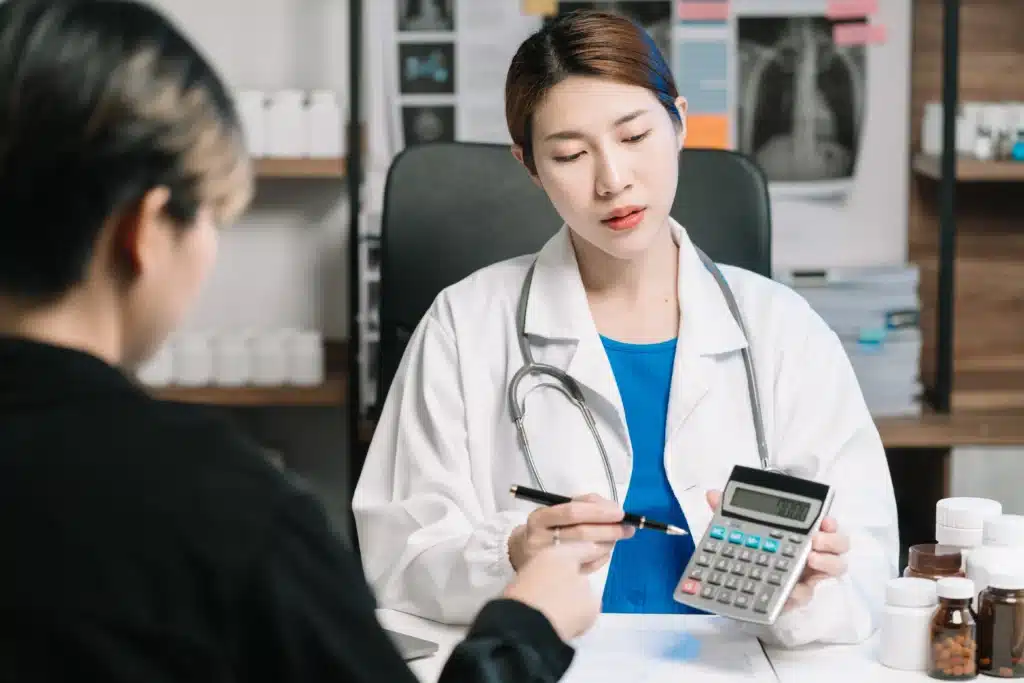 Doctor using a calculator to discuss spine surgery costs in the USA with a patient.