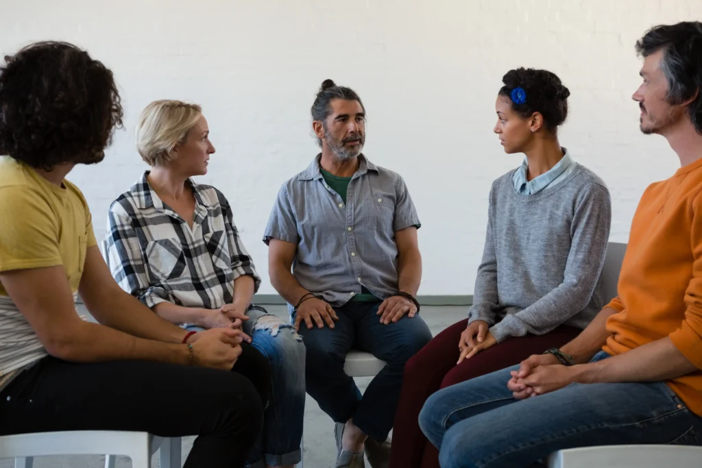 A group therapy session with participants attentively listening, showcasing the role of group support in managing chronic pain.