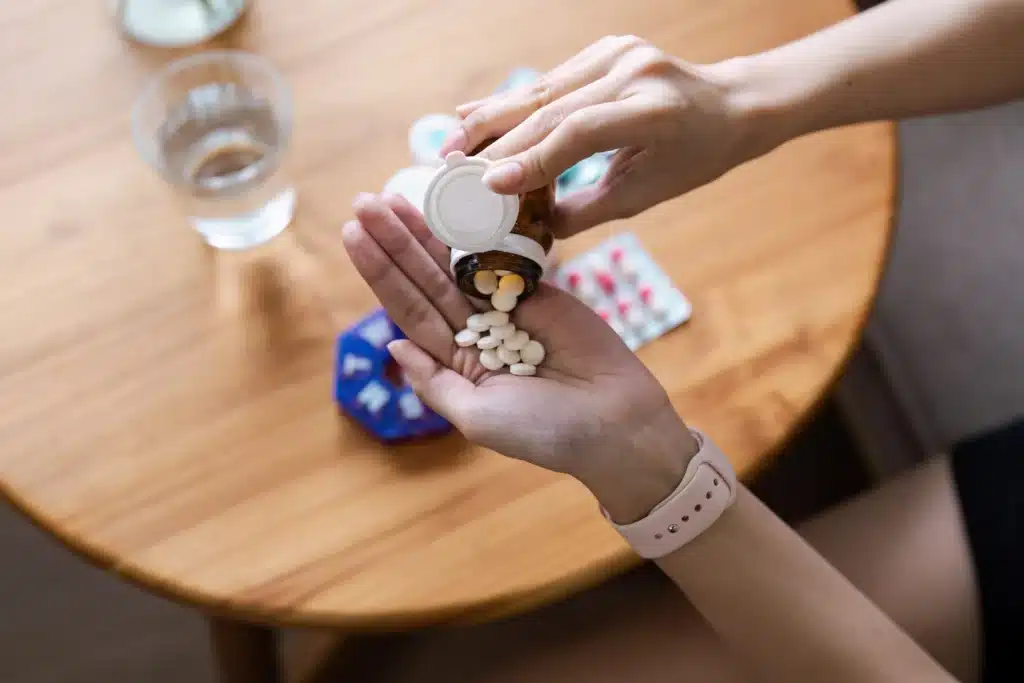 Hands pouring pills from a medication bottle, showcasing common non-opioid pain management drugs.