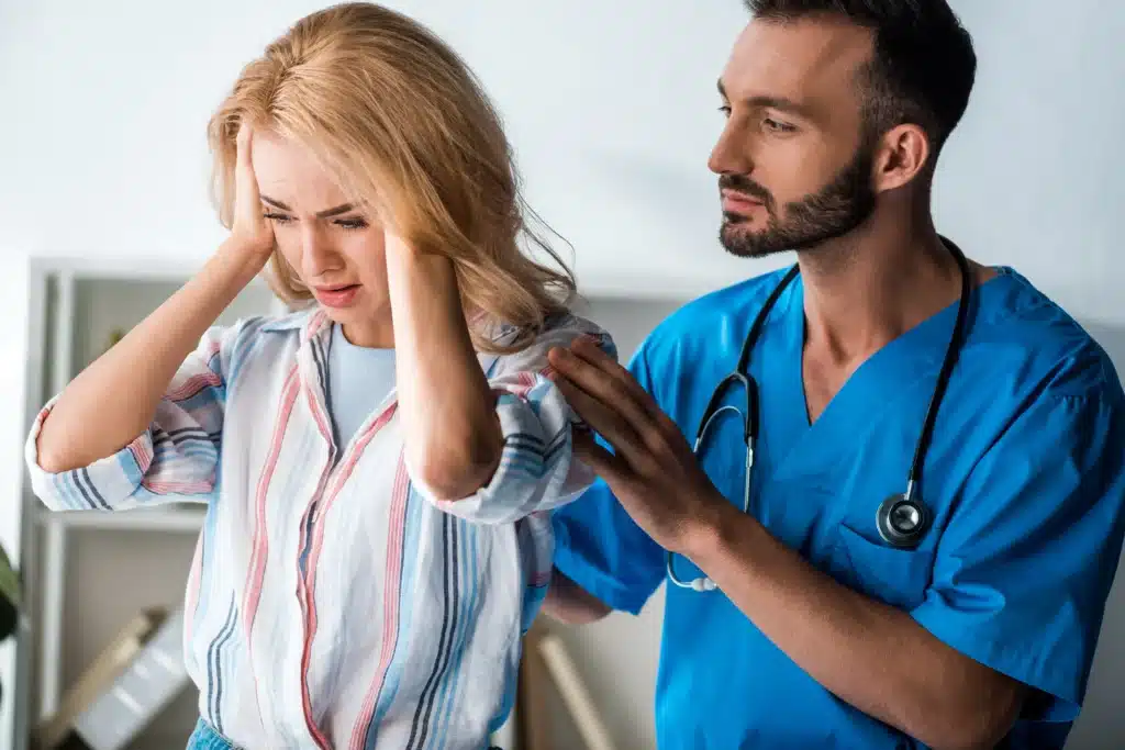 Bearded doctor providing support to a woman suffering from a headache, illustrating compassionate care in pain management in New York.