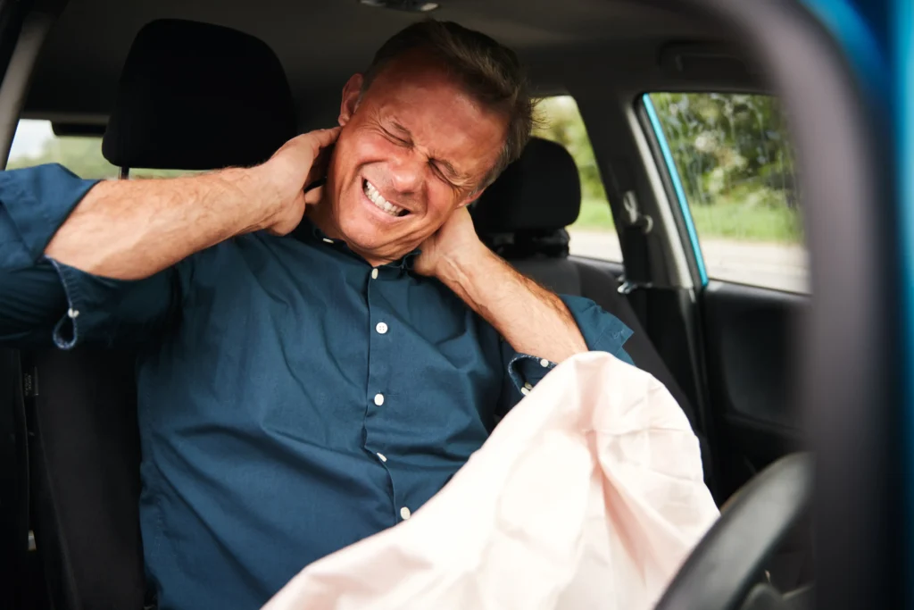 Driver experiencing neck pain after a car accident, emphasizing the risks of poor posture while driving.