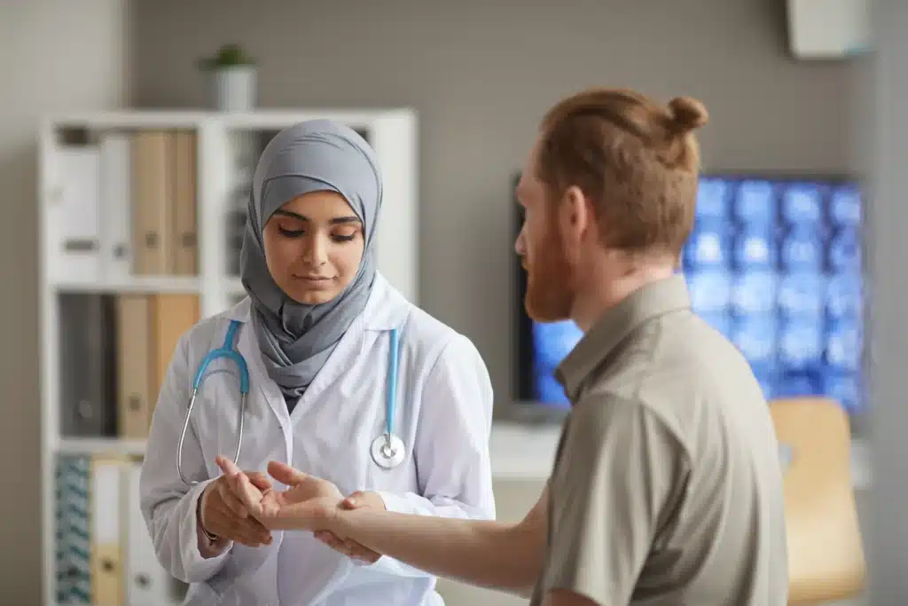 Female pain management nurse examining a patient’s wrist in a hospital on Long Island.