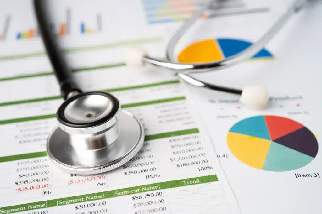 Stethoscope on spreadsheet with medical charts showing data analysis of spine surgery costs.