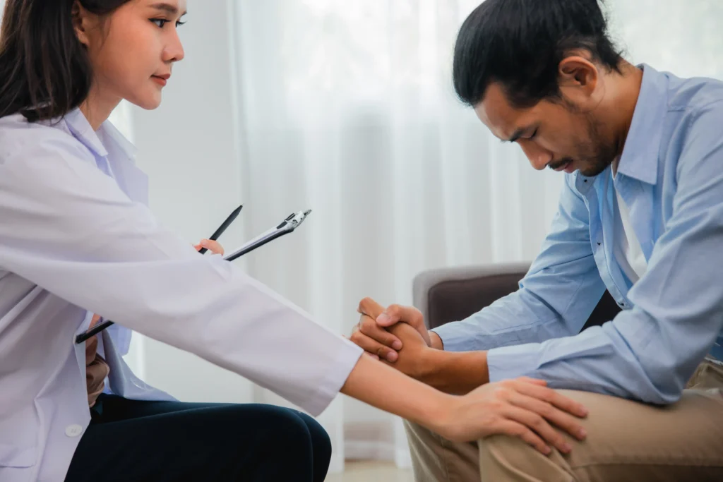 Psychiatrist offering support to a male patient during a consultation, using pain assessment tools for mental health and emotional well-being.