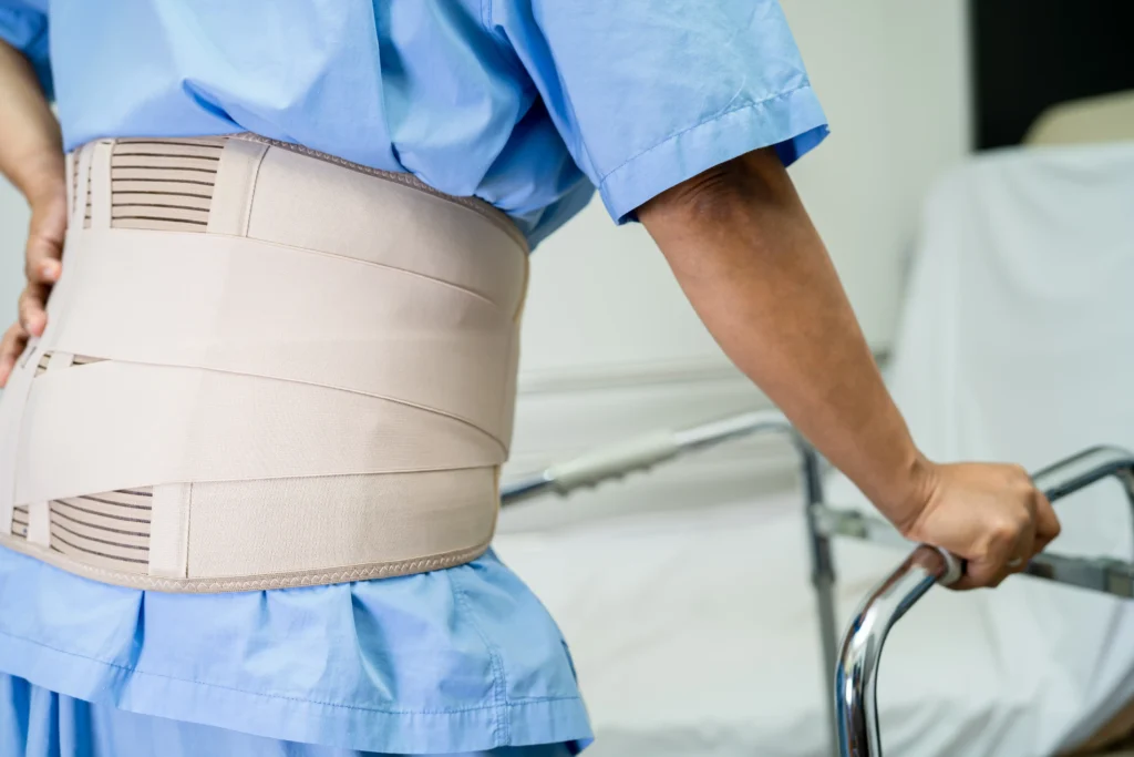 Patient recovering from spinal fusion surgery using a walker for support.