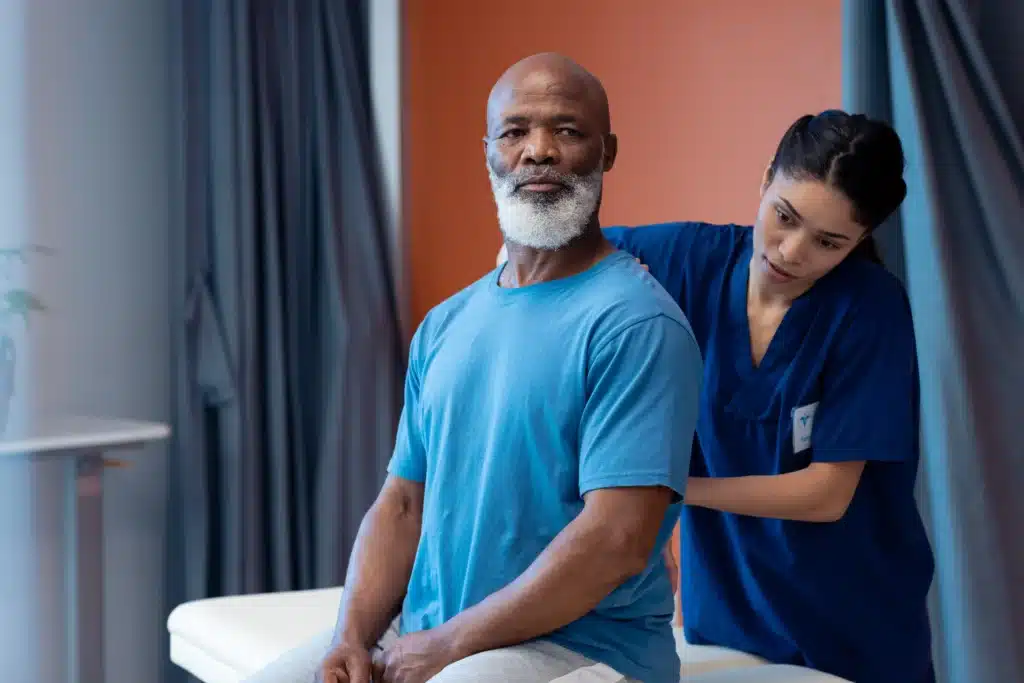 Diverse physiotherapist examining a patient’s back for fast pain relief during a therapy session.