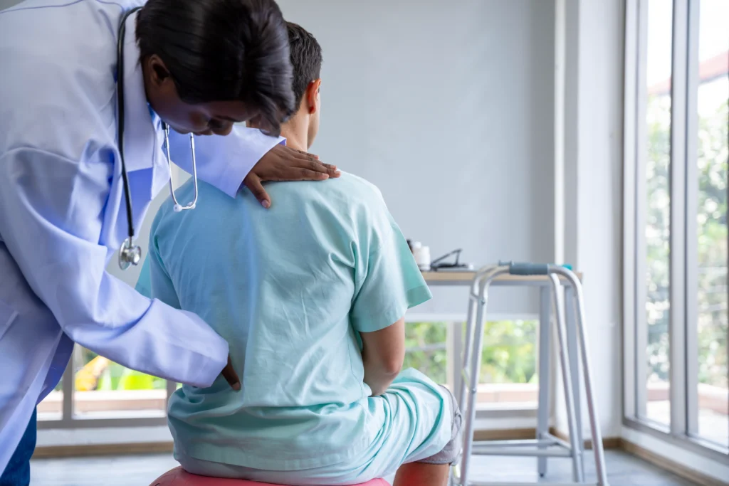 Doctor examining a male patient for back pain, showcasing the process of diagnosing back pain vs kidney stone pain.