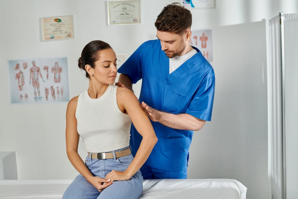 Handsome doctor performing a physical examination for SI joint pain in a clinic on Long Island.