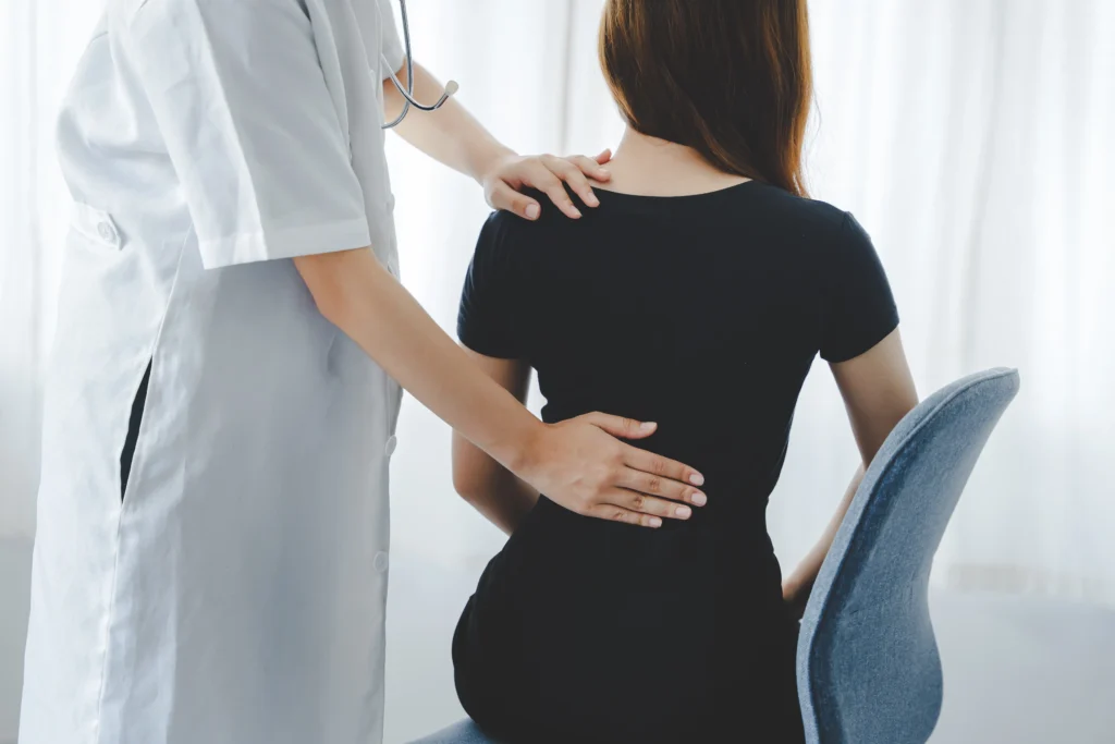 Female doctor assessing a patient’s back, emphasizing medical evaluations for back pain vs kidney stone conditions.