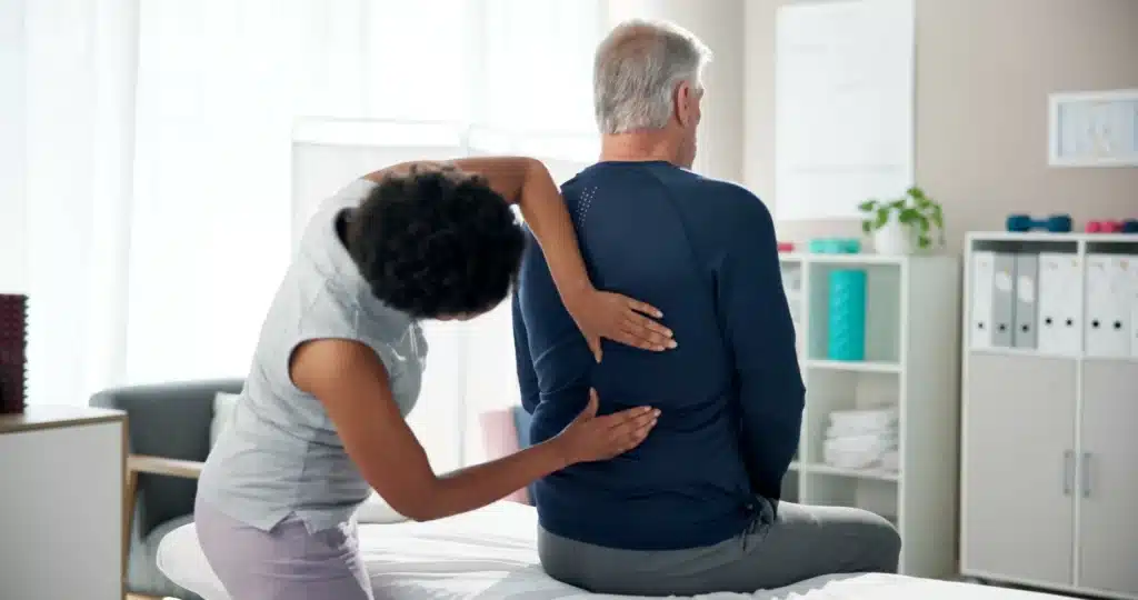 Senior man receiving back physiotherapy treatment for fast pain relief in a clinic setting.