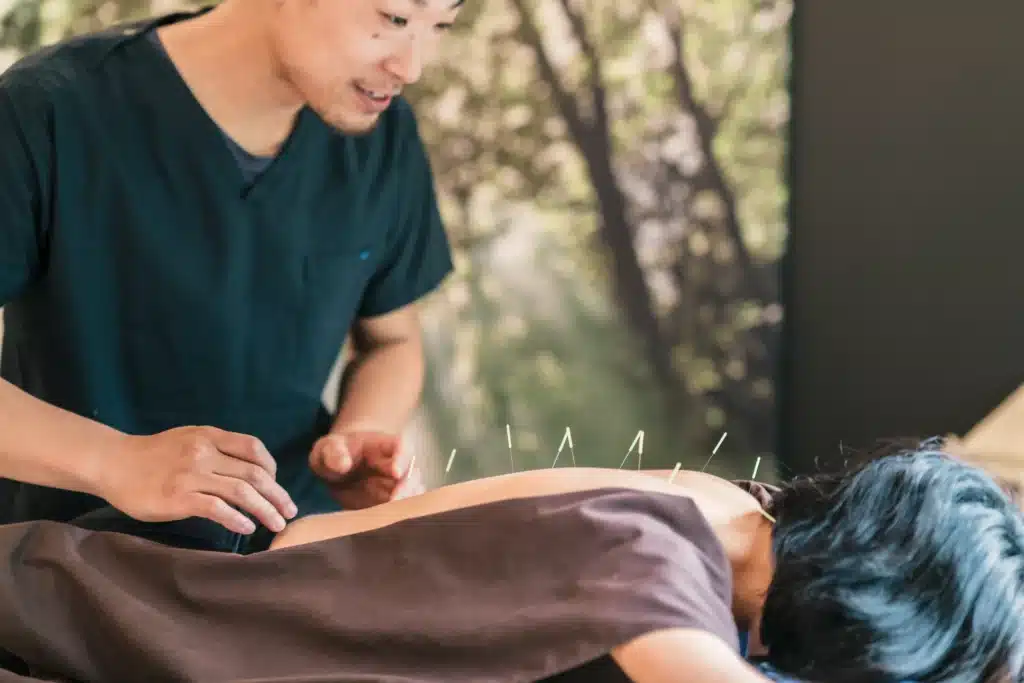 Acupuncturist treating back pain using acupuncture physical therapy techniques