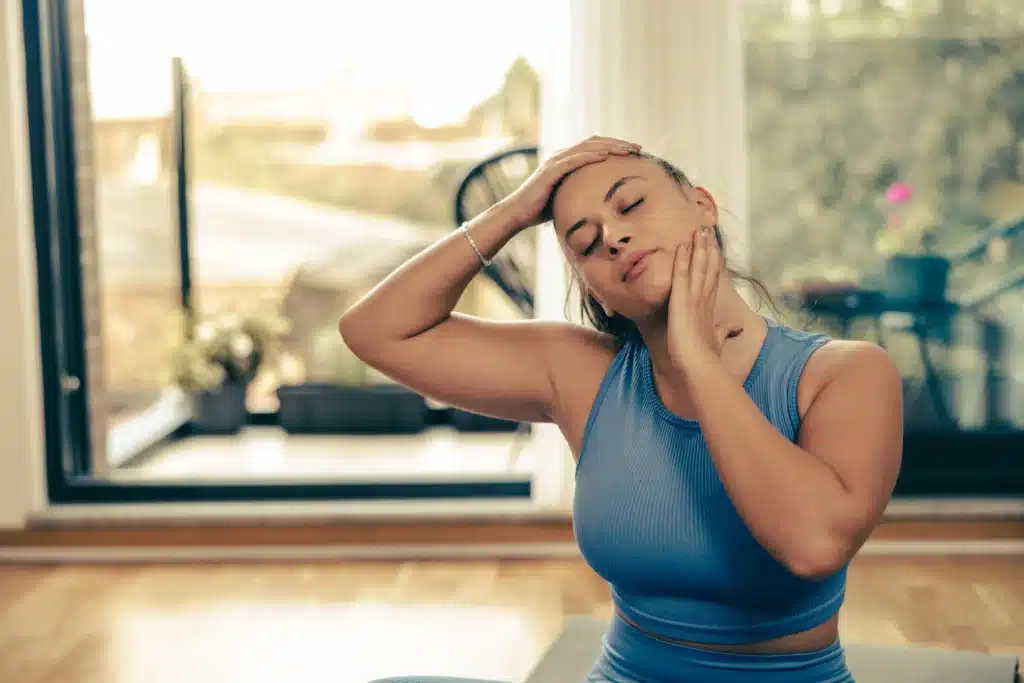 Woman performing yoga stretches for neck pain relief, complementing McKenzie Method exercises for home care.